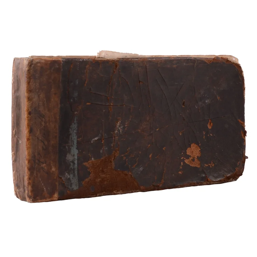 The closed book: a small, worn leather binding, dark brown with cracked and flaking patches, photographed against a white background