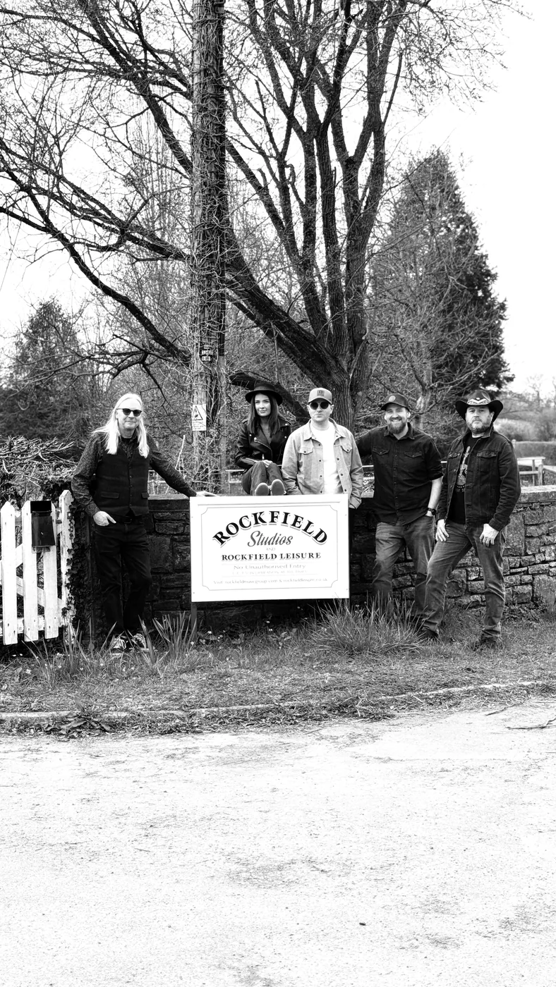 The five members of PORTICA photographed beside the Rockfield Studios sign at the entrance to the studio.